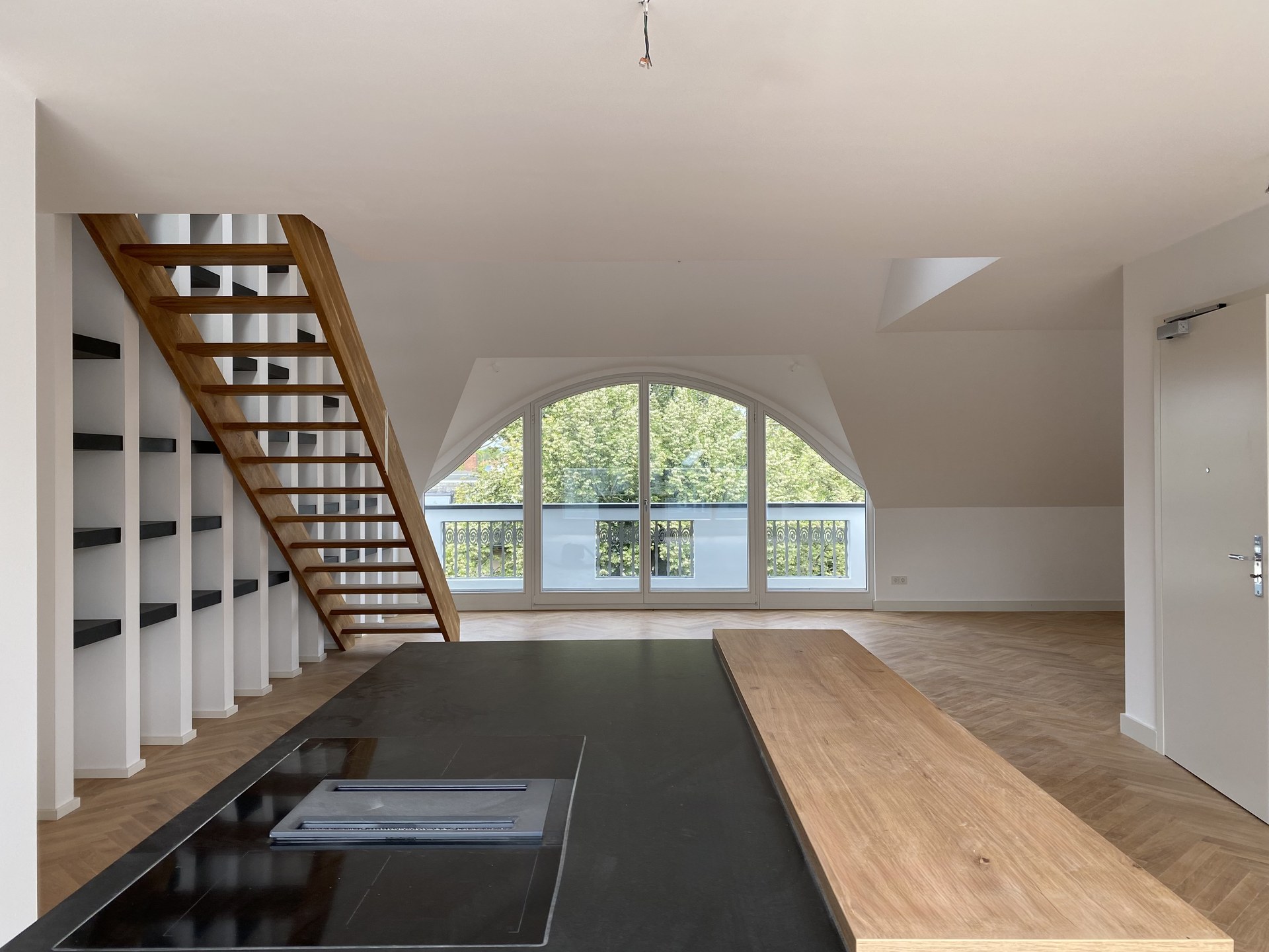 Maisonette Wohnküche mit Holztreppe, Bogenfenster und Kochinsel